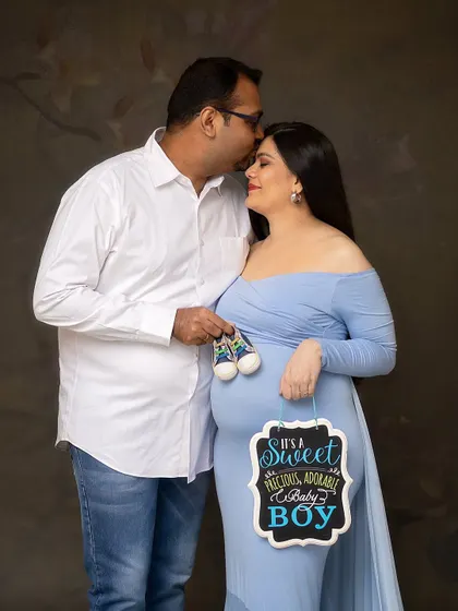 It's a boy! This couple chose to announce the gender with a chalkboard sign and adorable baby sneakers, making for a joyful and memorable portrait.