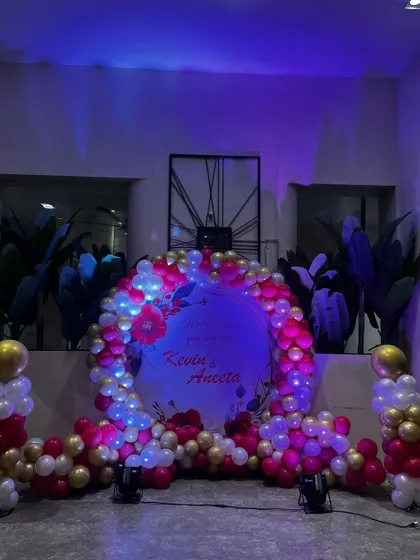 A circular ring backdrop is a popular and versatile choice for many events like engagements or anniversaries. Here, I have decorated it with a dense garland of pink, white, and gold balloons and soft lighting to highlight the couple's names.