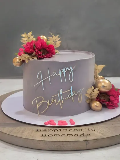 A sophisticated grey cake with pops of magenta from the floral decorations and gold accents, creating a modern and stylish look.