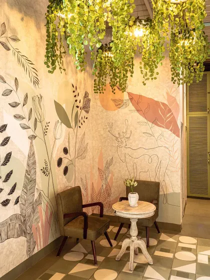 A cozy corner at Cafe Tesu, where a full wall mural with a similar flora and fauna theme creates an intimate and artistic seating nook.