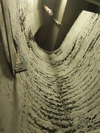 A detail view looking up into a narrow, textured concrete crevice within the store. This demonstrates the construction technique used to achieve the cave-like, excavated quality of the space, focusing on raw materiality.