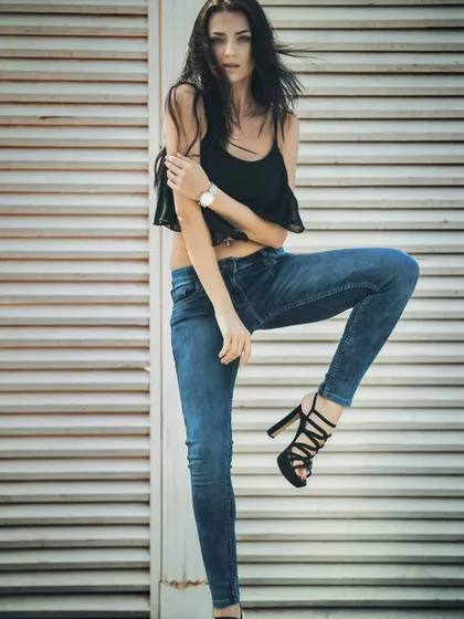 A classic fashion pose against a textured white shutter background. This shot highlights the fit of the jeans and the model's confident attitude, a staple for any western wear portfolio.