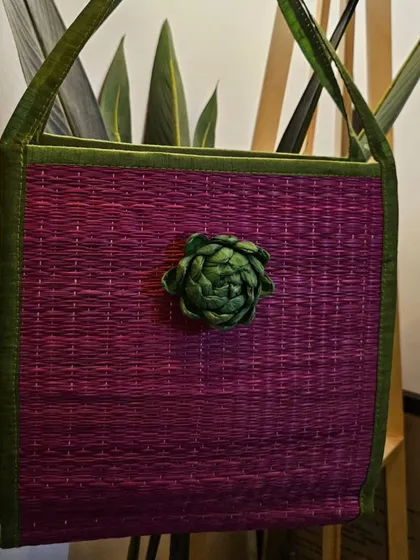 This tote bag is completely sustainable, made from natural river grass and adorned with a dry flower. It's a stylish way to make an eco-friendly statement.