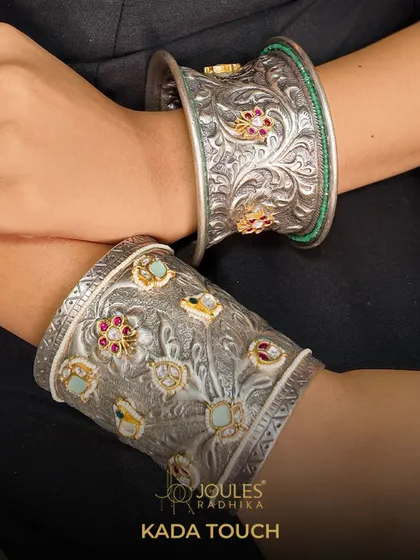 The Aalayaa Kada. A pair of wide, oxidized silver kadas with intricate floral carvings and subtle gemstone accents, perfect for a statement look.