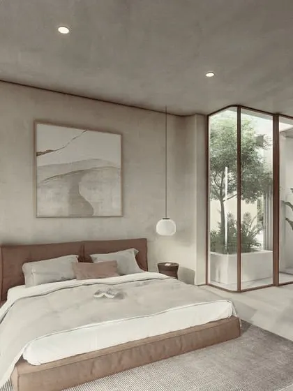 The interiors of the Pavilion homes are designed with a sense of lightness. This bedroom features soft, textured walls and a glass-enclosed courtyard, creating an experiential space that flows seamlessly into the bathroom.
