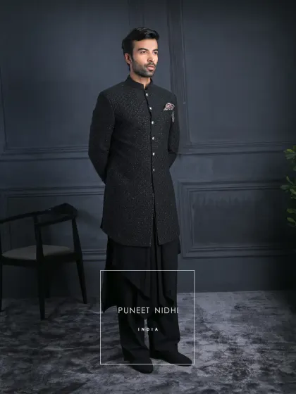 Not just attire, but an heirloom of style. This black self-textured achkan is adorned with regal silver buttons, flowing into draped kurta layers and wide trousers for unmatched elegance.