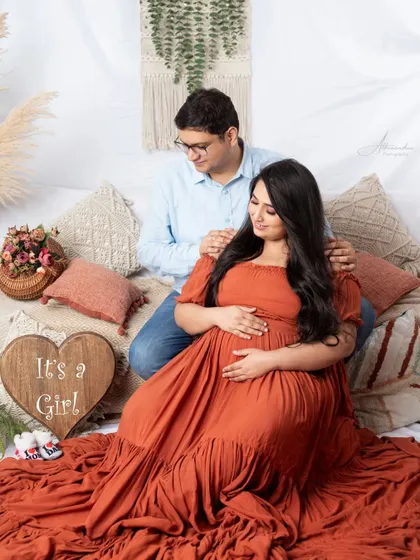 A sweet gender reveal. The "It's a Girl" sign, baby shoes, and the couple's loving gaze make this a perfect announcement photo.