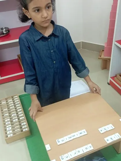 This child is using the movable alphabet to compose sentences. This material allows for complex expression and helps children understand grammar and sentence structure in a tangible way.