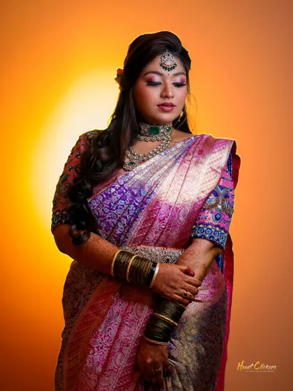 A beautiful bridal portrait showcasing her intricate saree and jewelry. The warm, solid background makes the colors of her outfit stand out.