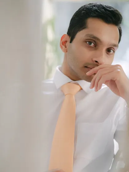 A close-up, introspective portrait of a groom. The soft focus and his thoughtful gaze create a soulful and compelling image.