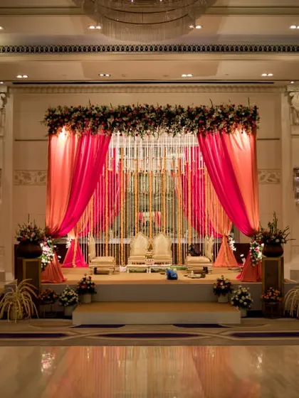 A grand and opulent stage setup for a wedding reception at ITC Gardenia, using rich pink drapes and floral arrangements to create a feeling of royalty.