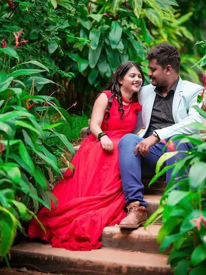 A loving gaze shared between a couple seated on steps in a vibrant garden.