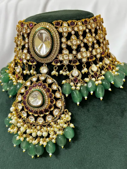 A close-up view of one of my most detailed bridal chokers for rent. This piece features intricate Kundan work, green beading, and a large central pendant, perfect for making a statement.