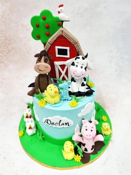 We bring the charm of the countryside to your party with this delightful farm animal cake. A classic red barn is surrounded by a friendly cow, horse, pig, and chickens, creating a vibrant and cheerful pastoral scene for a young child's birthday.