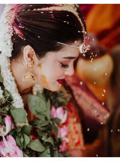 A beautiful close-up of the bride during the 'talambralu' ritual, with rice grains showering down on her.