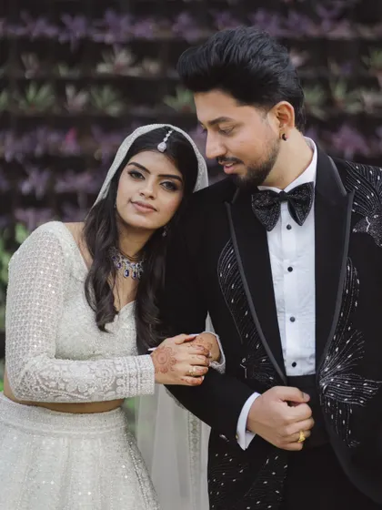 A close-up shot capturing a gentle, loving glance between the couple. The bride's traditional maang tikka beautifully complements her modern white lehenga.