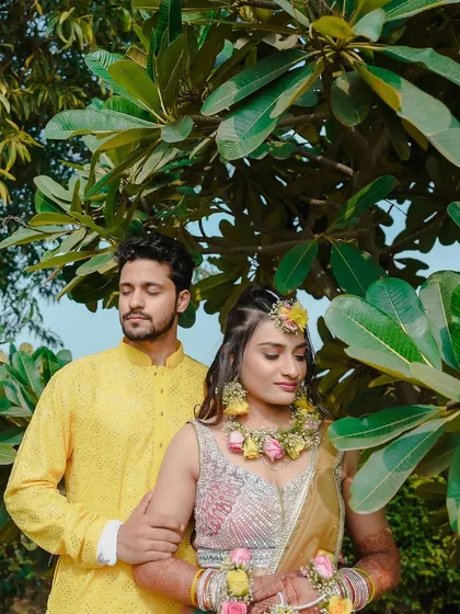 A romantic portrait of the couple amidst lush greenery during their Haldi event. The bride is adorned with beautiful floral jewelry.