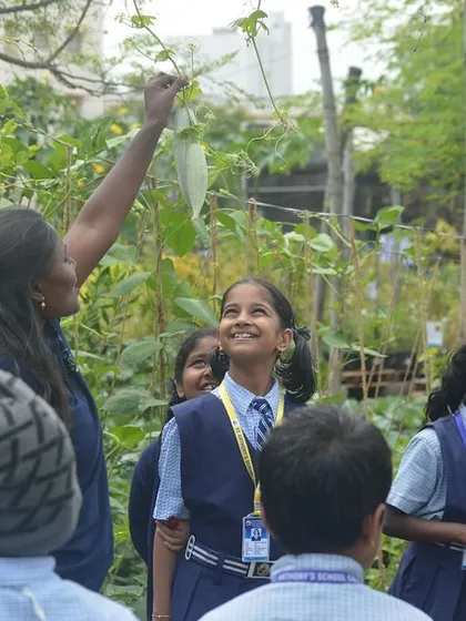 A student's face lights up as she learns about a climbing vegetable plant. These are the moments of connection to nature that I aim to create.
