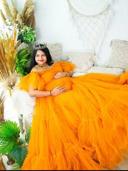 This bright orange tulle gown makes a bold and cheerful statement. The wide shot showcases the full expanse of the dress amidst our indoor studio's botanical and boho elements.
