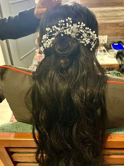 A chic and elegant half-up, half-down hairstyle. The look is finished with a beautiful pearl hair accessory, making it perfect for a sangeet or reception.