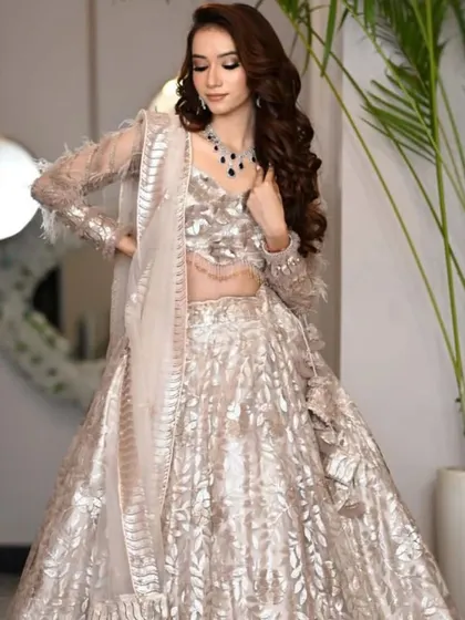A sophisticated champagne-gold lehenga-gown with delicate feather details on the sleeves. A perfect fusion look for a modern reception.