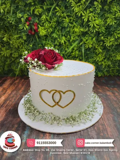 An elegant anniversary cake with two intertwined golden hearts and a fresh red rose on top. A simple and beautiful symbol of your love.