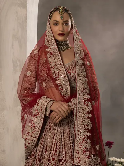 The beauty of a bridal look is in the details. Here, the sheer dupatta with its embroidered border frames the bride's face, while the bold lip and choker add a touch of confident glamour.