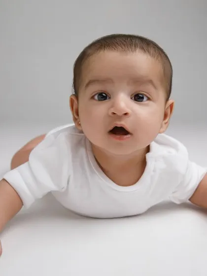 Conquering tummy time! This is a big milestone for little ones, and this baby is showing off his strength with a curious expression.