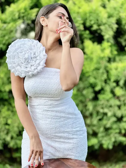 A chic and modern white one-shoulder bodycon dress. The large floral detail on the shoulder is handcrafted and makes this simple dress a statement piece.
