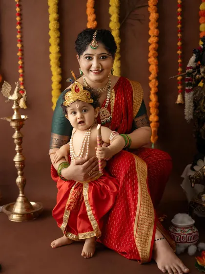 A regal portrait of a mother and her baby Krishna, who is holding his flute.