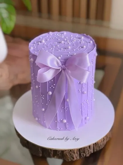 This pretty purple bow cake is a study in texture. Learn to create the vertical buttercream lines, add delicate pearl sprinkles, and tie the perfect satin-finish bow.