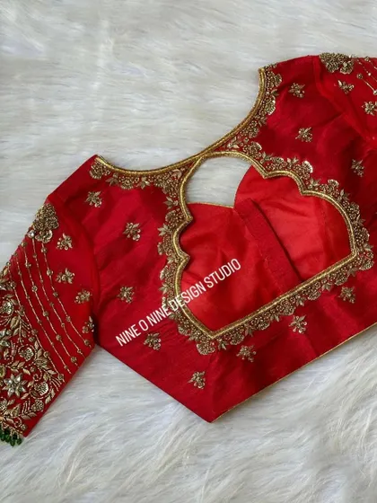 A masterpiece for our bride Madhuri. This classic red bridal blouse is heavily embroidered with zardosi and stone work, featuring a beautiful heart-shaped cutout on the back. The sleeves are a canvas of intricate floral patterns, making it a truly royal piece.