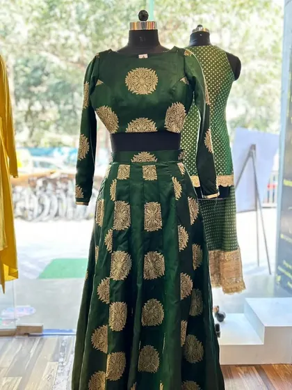This custom brocade silk ghagra in a rich emerald green showcases a different side of bridal wear. The full-sleeved crop top and flowing skirt feature classic brocade motifs, creating a sophisticated and regal look perfect for a sangeet or reception.