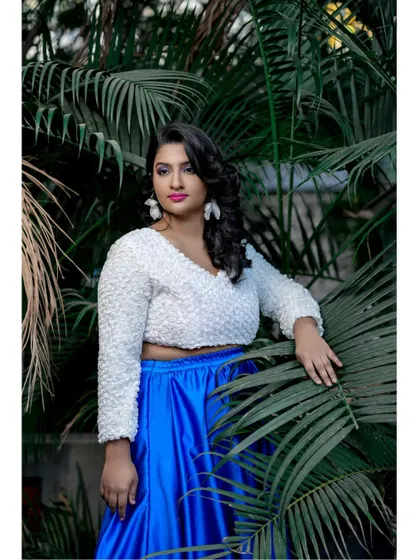 A close-up of the white 3D floral crop top paired with the vibrant blue satin skirt. The texture of the top adds a unique and fashionable element to the outfit.