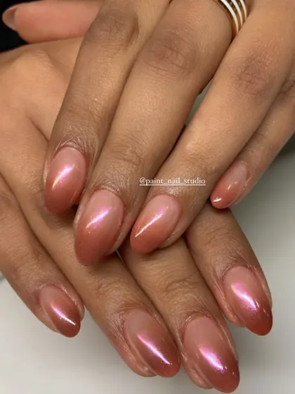 A warm, shimmery ombré on short, oval-shaped nails. The coppery-pink tones are flattering on every skin tone.