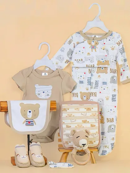 A styled flatlay of a baby clothing set. Hanging the clothes gives a boutique feel, and the arrangement shows all the matching pieces, including a onesie, bib, and booties.