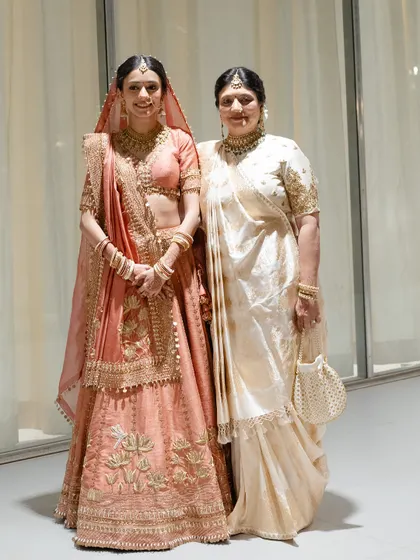 The bride with her mother, both looking radiant in their respective wedding day outfits, a beautiful mother-daughter portrait.