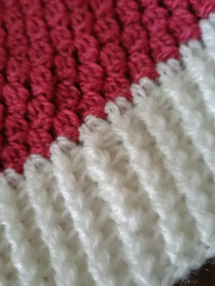 A detailed shot of the Flora beanie, showing the transition from the pink cluster-stitch body to the white ribbed brim. The textures complement each other nicely.