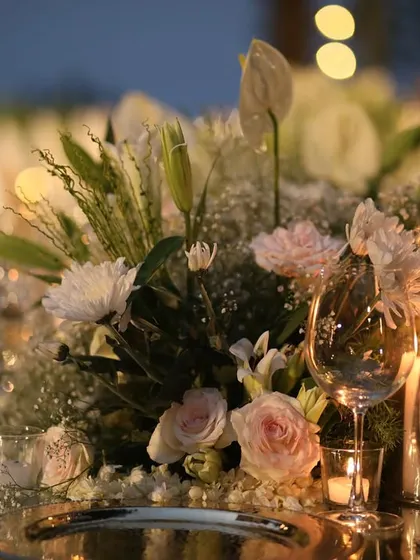 A close-up of the Kasauli dinner tablescape, showing the elegant combination of silver charger plates, blush napkins, and a soft floral arrangement illuminated by candlelight.