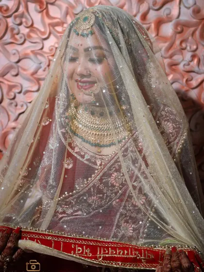 A shy bride under her veil. This classic pose is timeless and captures the modesty and grace of a traditional Indian bride.