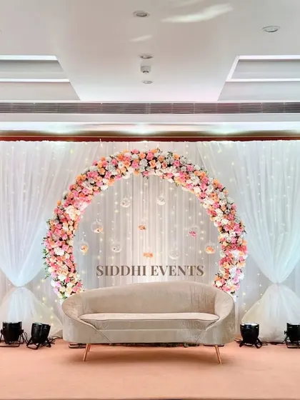 This dreamy ring ceremony setup features a circular floral arch with hanging glass baubles, creating a delicate and magical focal point behind the couple's seating.