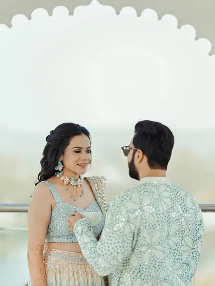 A beautifully framed shot of the couple under a white archway, their interaction feeling natural and romantic.
