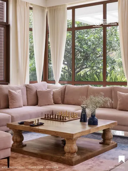This living room from our 'A Walk in the Clouds' project features a large, comfortable blush-toned sectional sofa, perfect for family gatherings. The large windows connect the indoor space with the lush greenery outside.