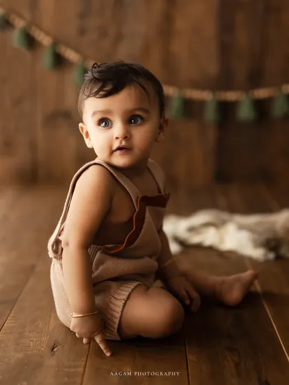 A sweet and curious toddler looking up, captured in a rustic setting. The natural light and wooden textures create a warm and inviting portrait.