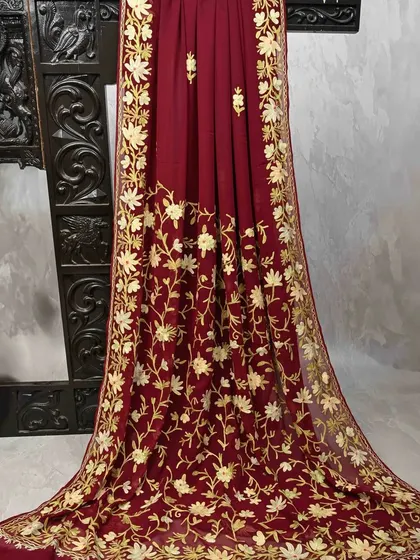 This deep maroon georgette saree features stunning all-over gold floral embroidery. It's a rich and opulent piece that drapes beautifully, perfect for a wedding reception.