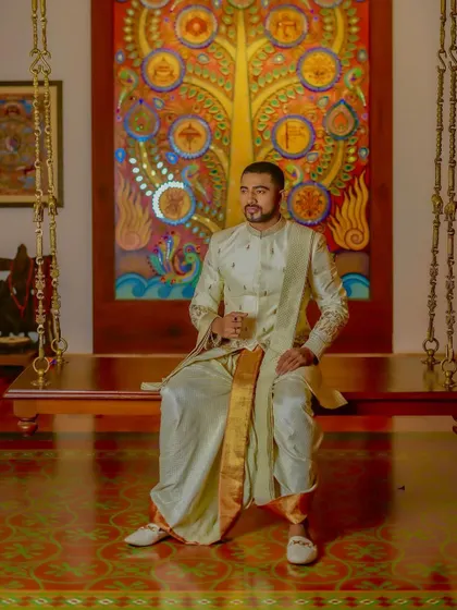 A full look at the off-white embroidered sherwani set. The gold-bordered sash adds a touch of traditional grandeur, while the tailored fit of the jacket keeps the silhouette modern.
