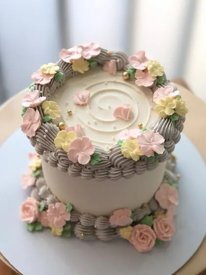A lovely floral cake with a mix of pastel-colored, hand-piped flowers.
