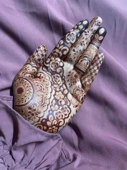 A close-up of a detailed design, showing the combination of a large mandala, floral fillers, and patterned fingers.