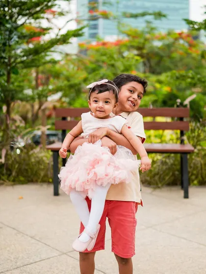 A protective older brother holds his baby sister, both looking adorable for the camera. Capturing sibling bonds is one of our favorite things.