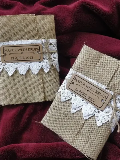 A look at the exterior of our jute and lace wedding invitations. The natural texture of the jute is softened by a delicate white lace band and a custom wooden tag, creating a charming first impression.